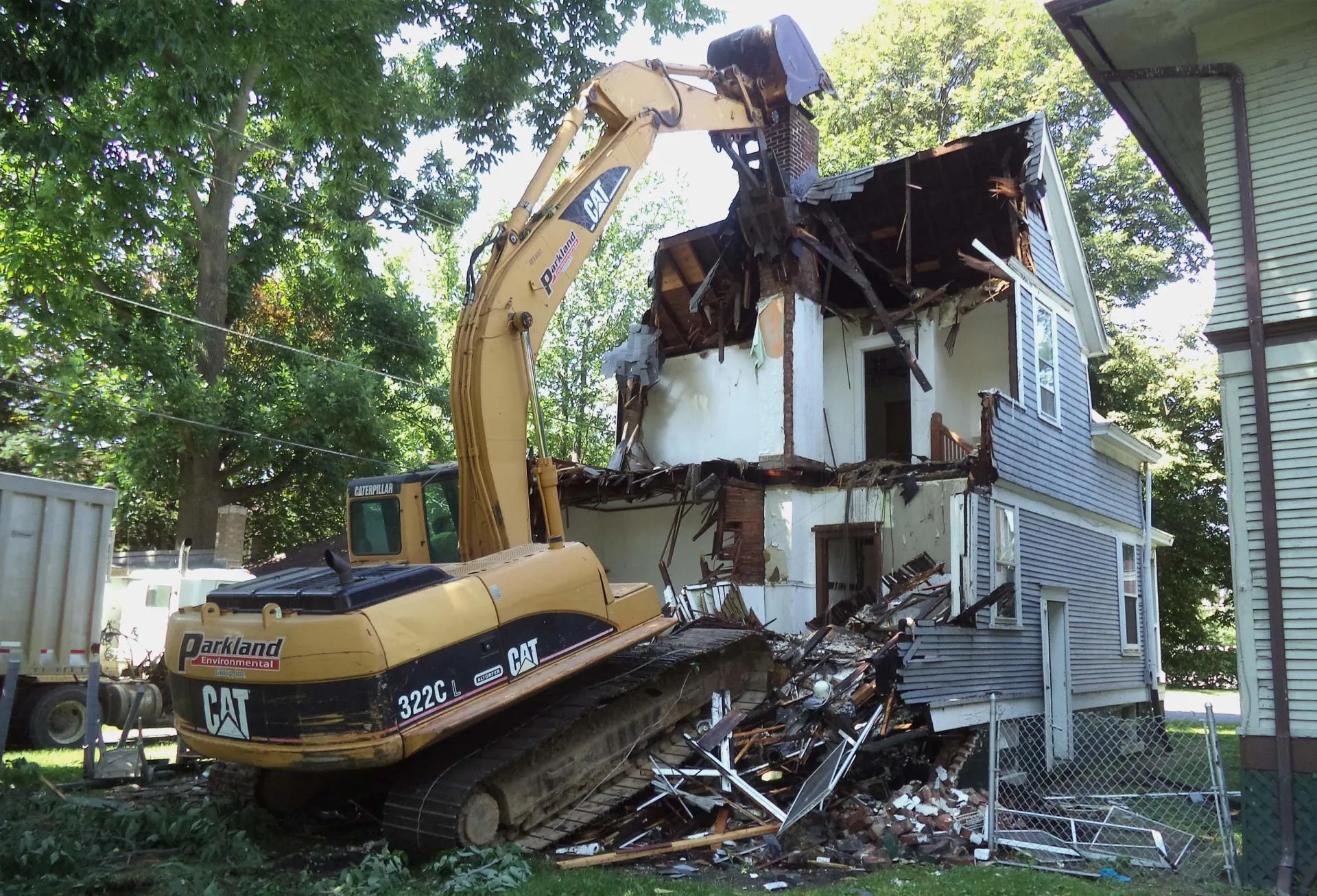 Worker destroying home with excavator