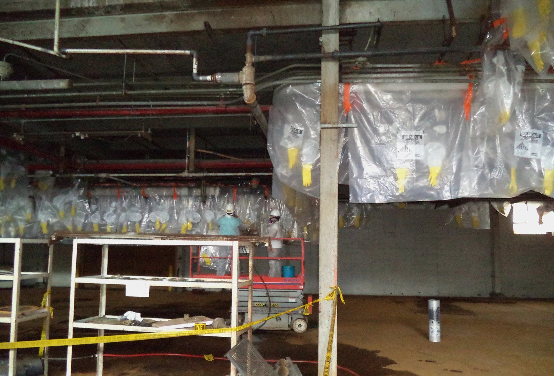 Professionals in protective suits remove asbestos on a wall