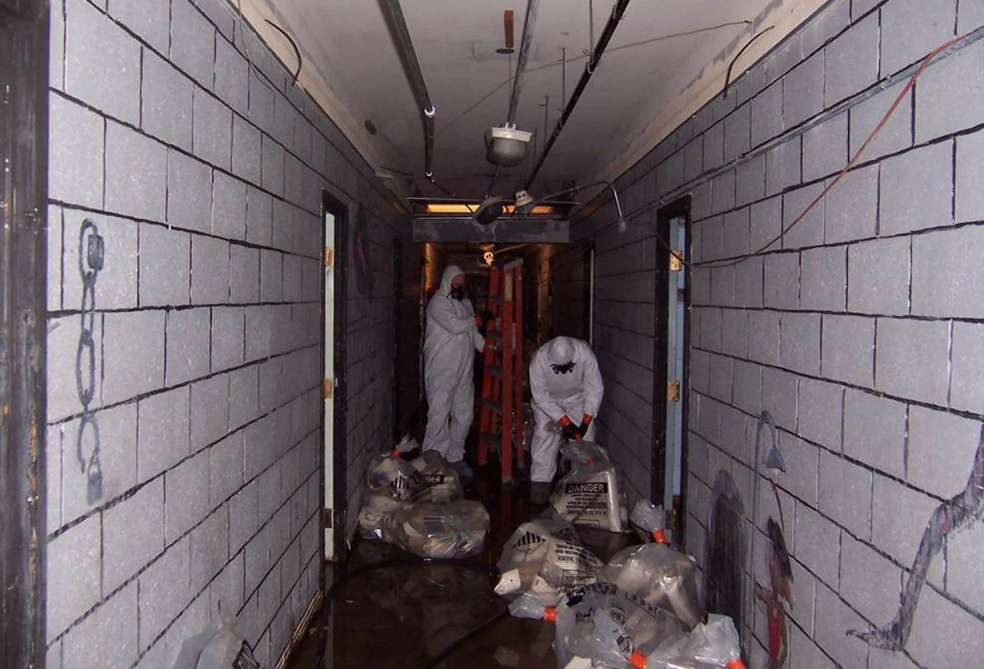 Two workers in hazmat suits cleaning up building